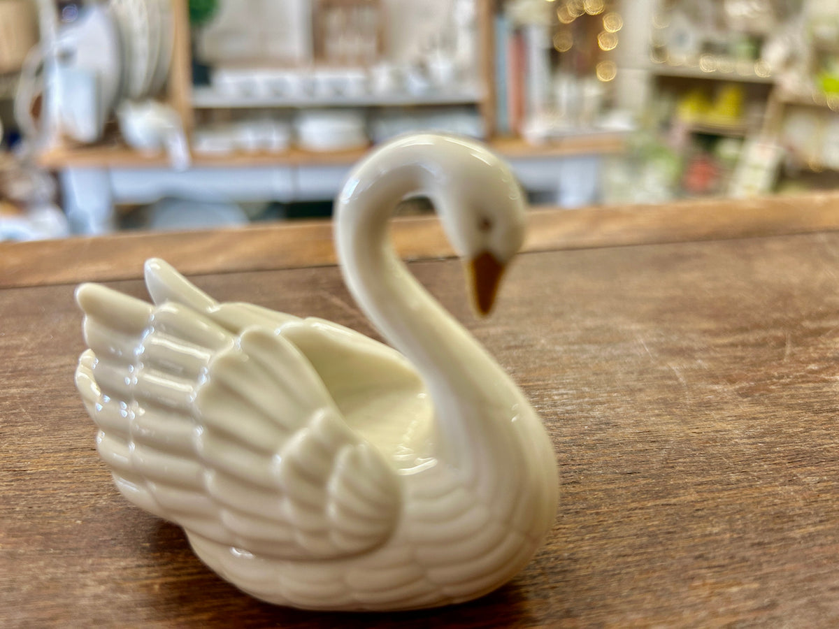 Cream porcelain swan cake topper with neck raised, angled view with wings extended.