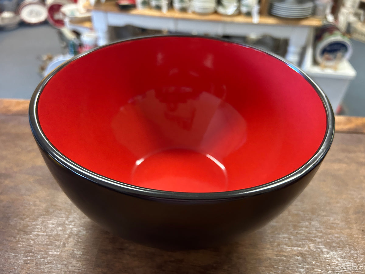 Black ceramic bowl with glossy red interior and thin white rim