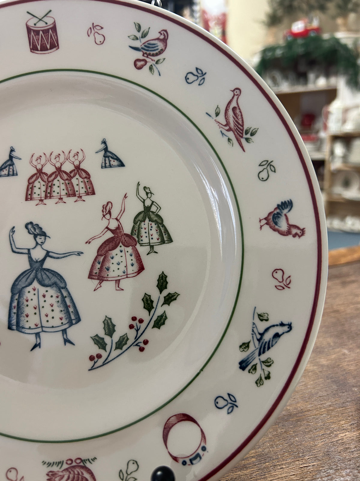Multicolor Christmas plate rim with birds and vine accents, featuring blue and red dolls.