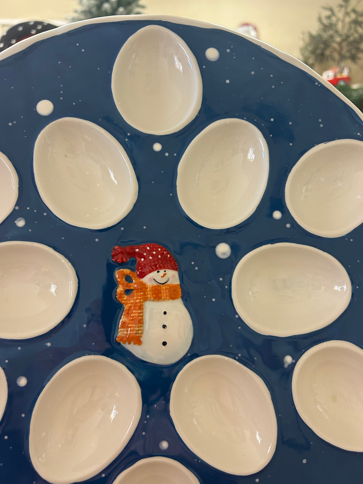Blue ceramic deviled egg tray with snowman graphic and white egg cup wells