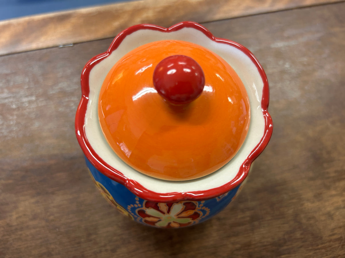 Ceramic sugar bowl lid with orange top, red scalloped rim, and blue sides