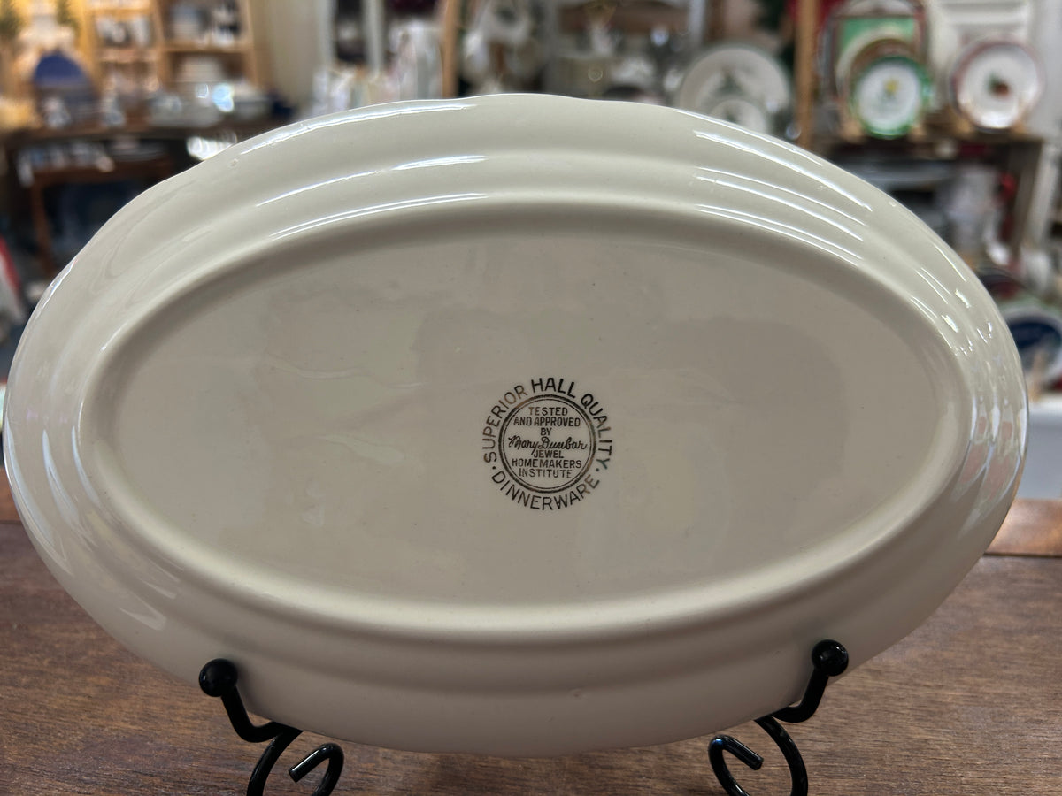 Oval white porcelain gravy plate bottom with maker stamp and black display stand
