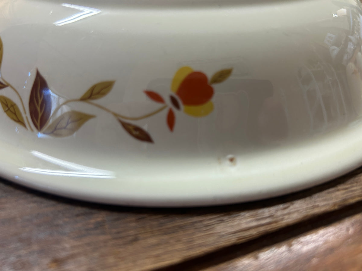 Close-up of white ceramic rim showing orange flower and brown leaf accents