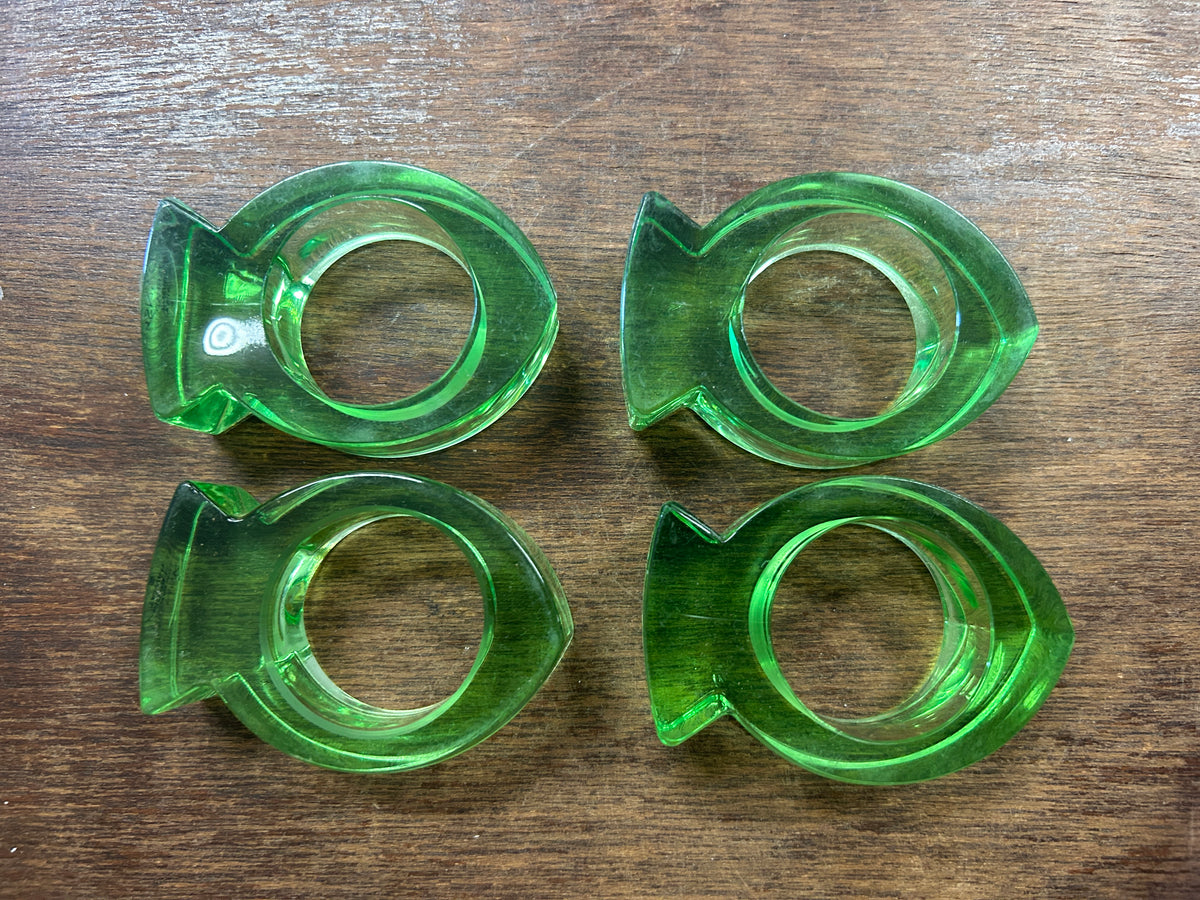 Set of four green acrylic napkin rings with circular openings and sculpted edges