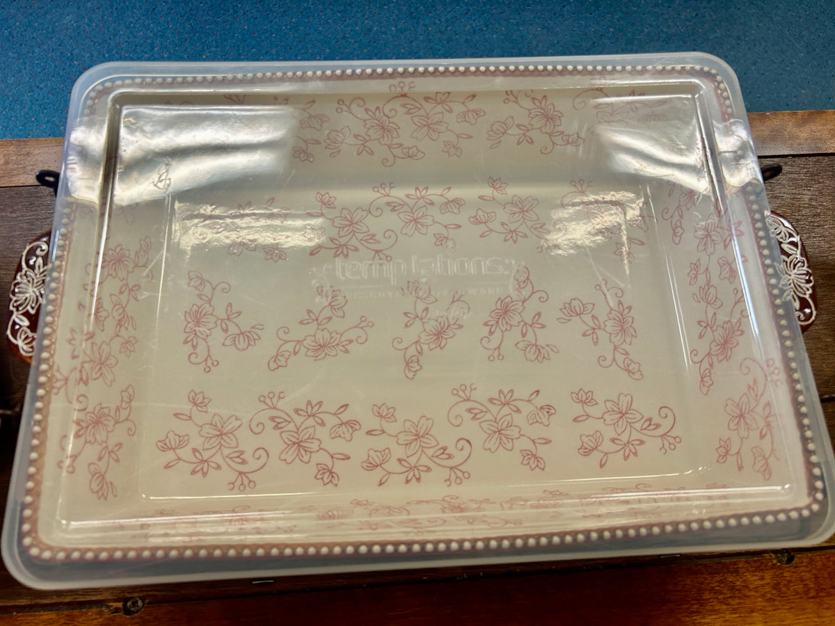 Clear baker lid with light floral lace print and beaded trim, on rack