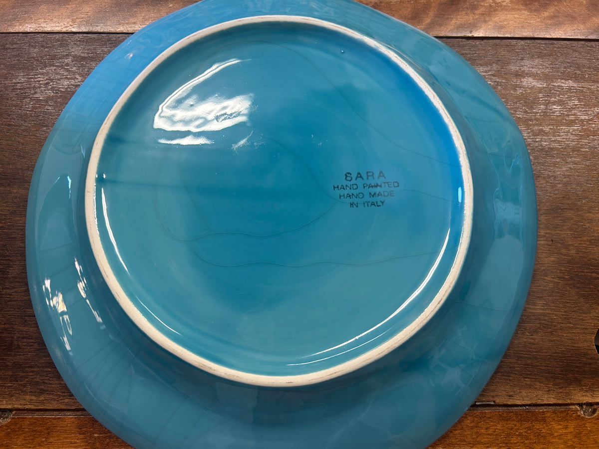 Blue serving bowl underside with a raised foot ring and Sara Italy maker's mark