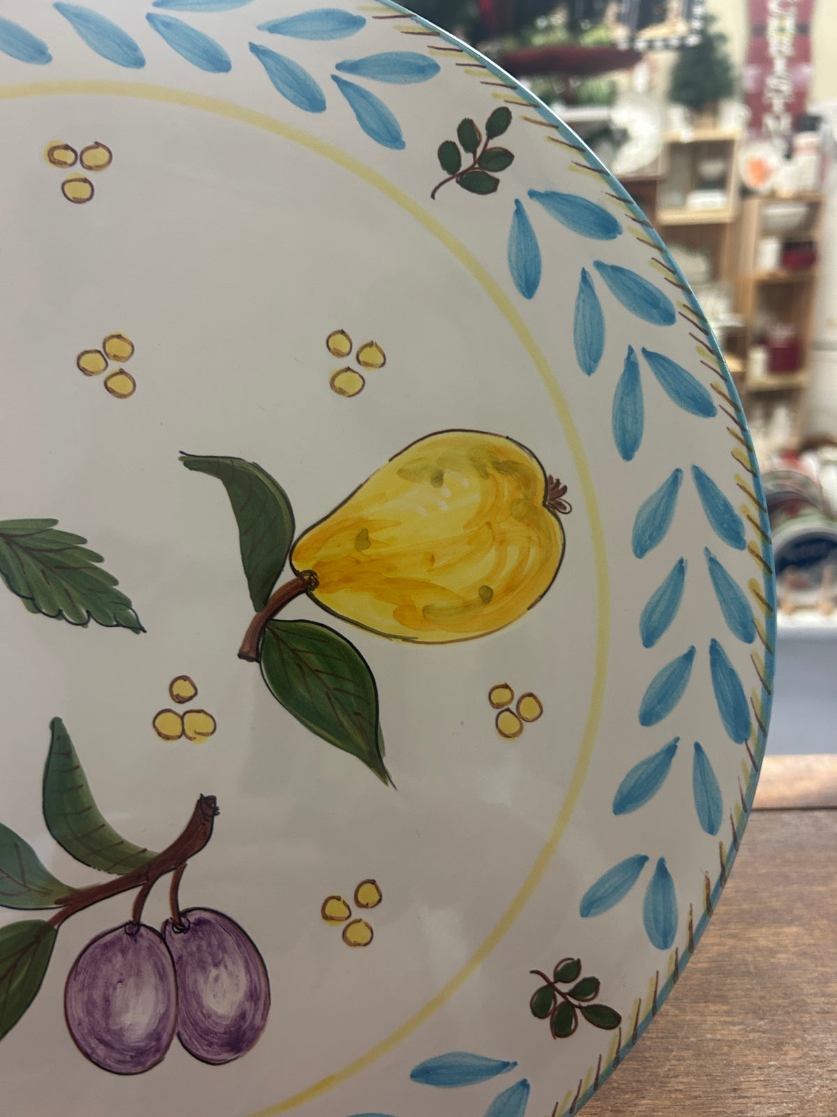 Close-up of platter showing yellow pear, purple plums, and blue leaf border