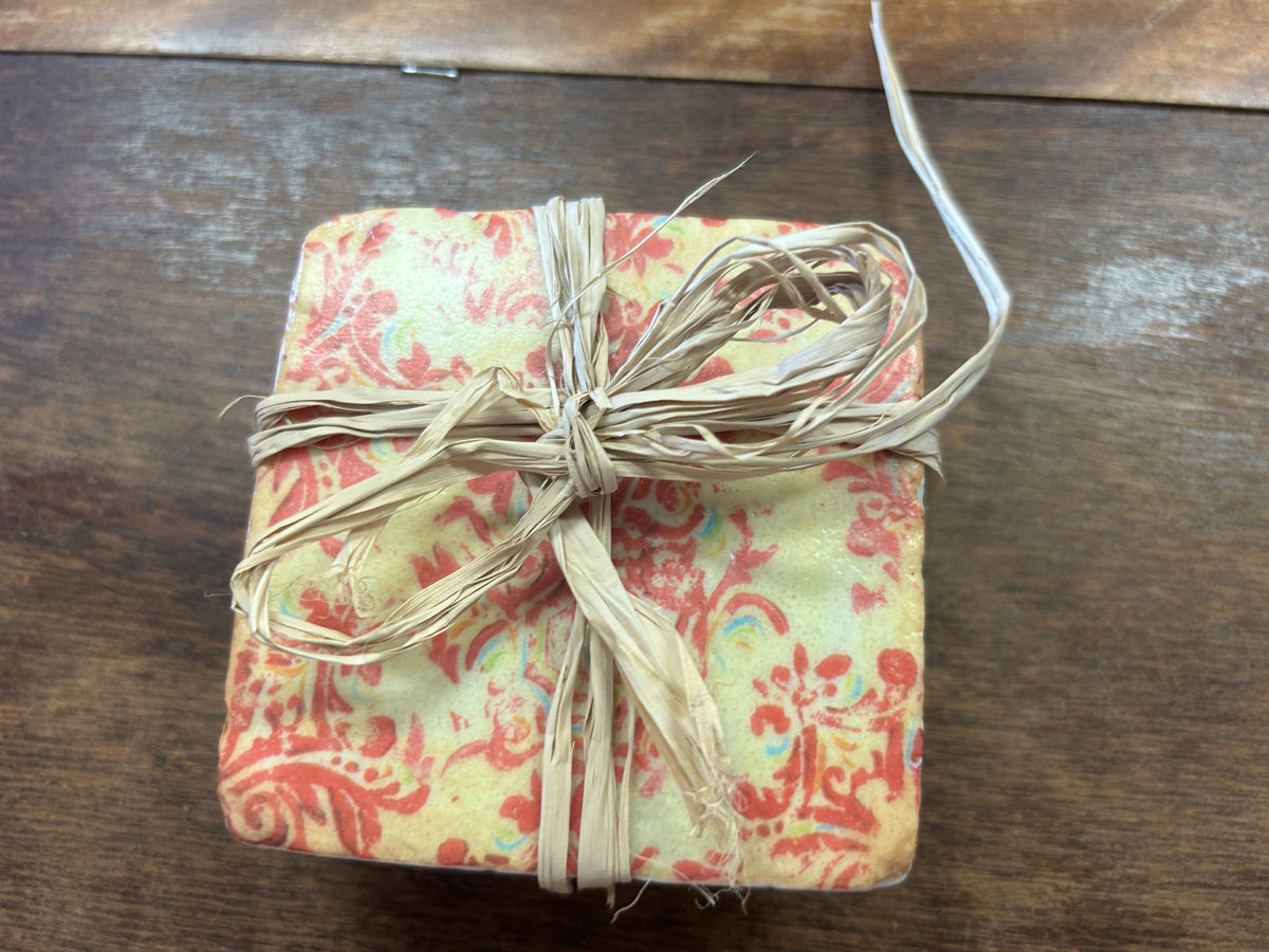 Floral-patterned square coaster top in coral, green, and cream, tied with raffia