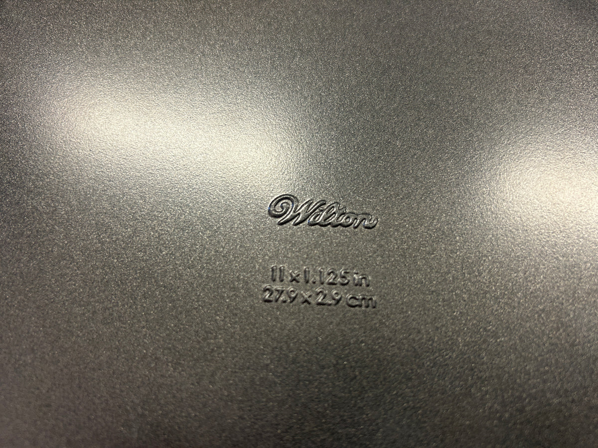Close-up of Wilton branding and 11 x 1.125 inch size marking on the pan base