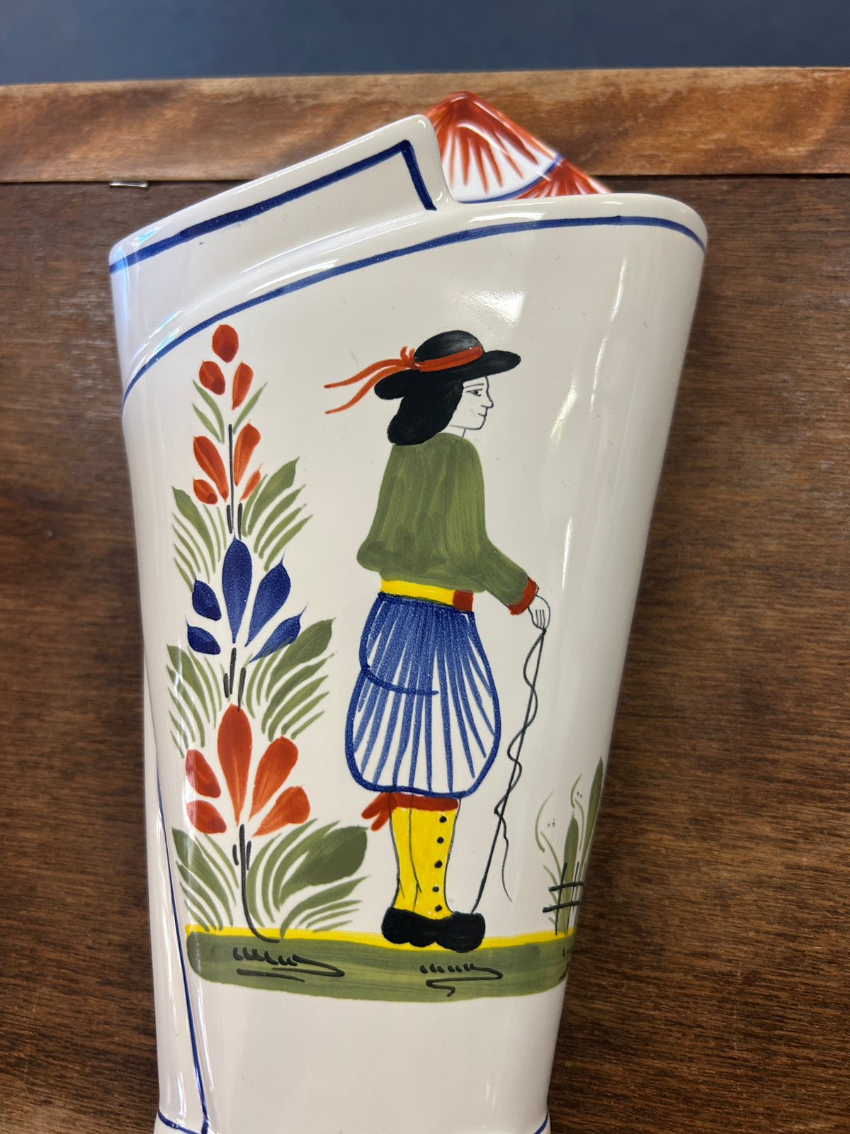Quimper ceramic wall vase painted with a figure in a green top and blue skirt