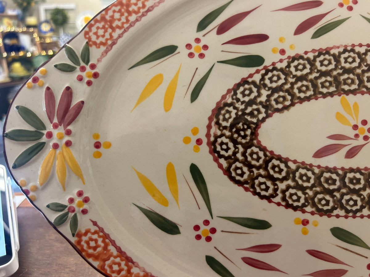 Oval serving platter close-up with multicolor botanical accents and patterned center