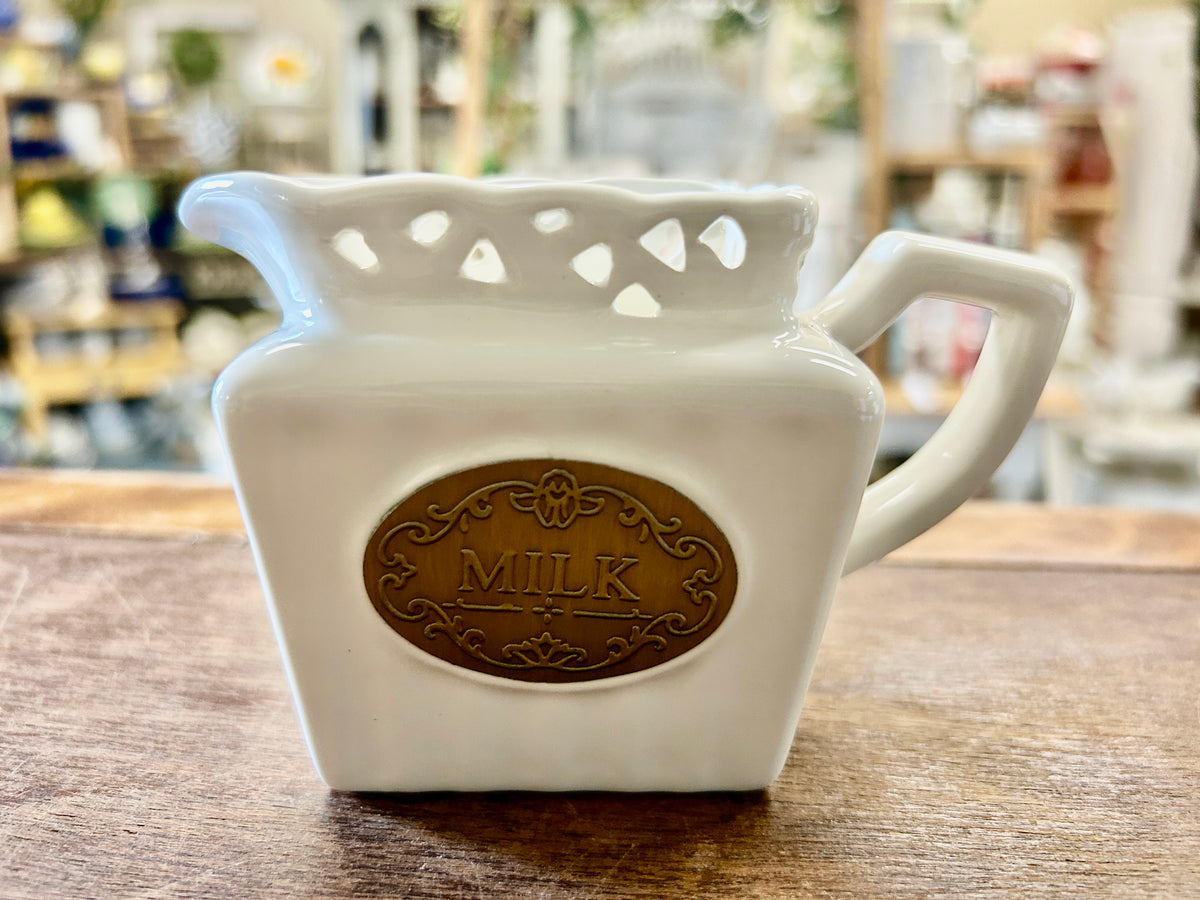 Square ceramic milk creamer in cream, cutout rim, dark brown 'MILK' medallion, side handle