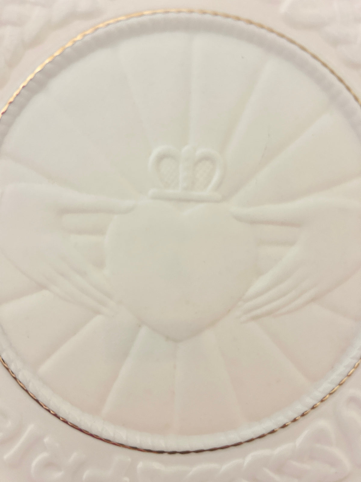 White ceramic Claddagh heart box lid close-up with embossed heart and gold rim