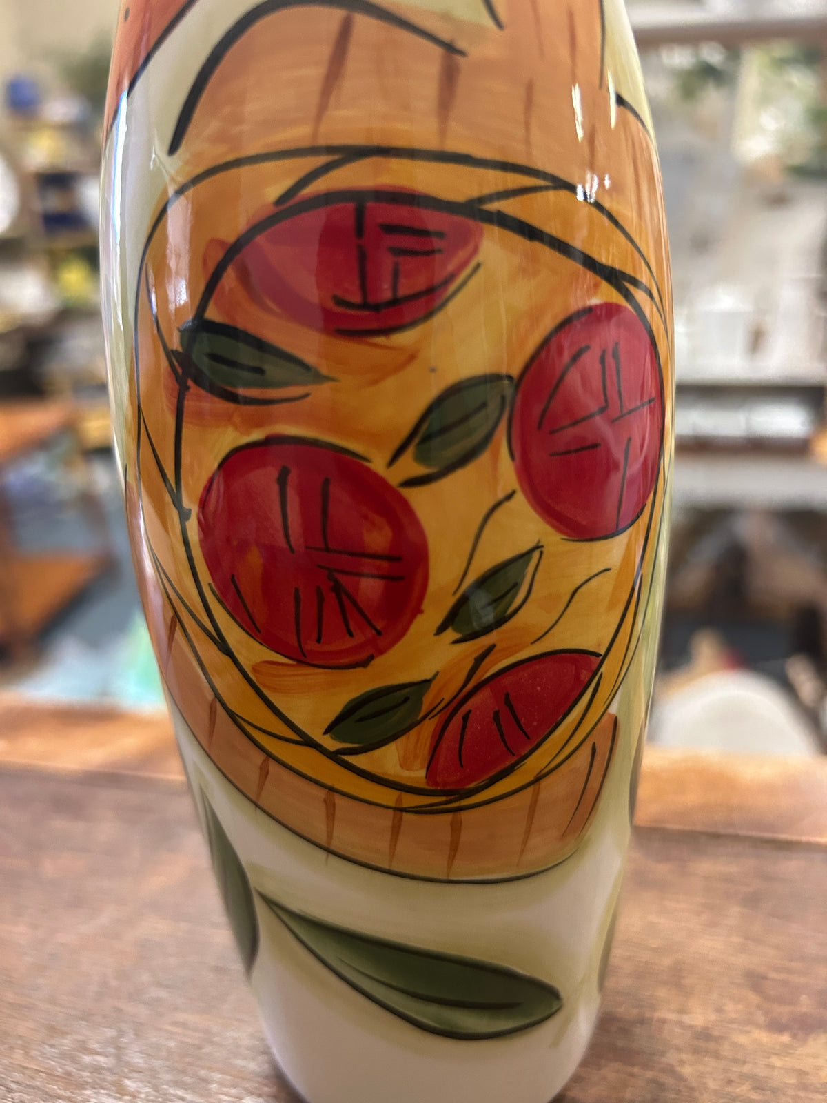 White olive oil cruet close-up with painted red fruit and green leaves, cork stopper