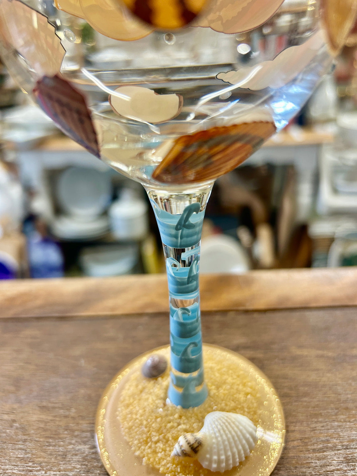 Tall beach themed wine glass with shell and fish artwork, blue striped stem