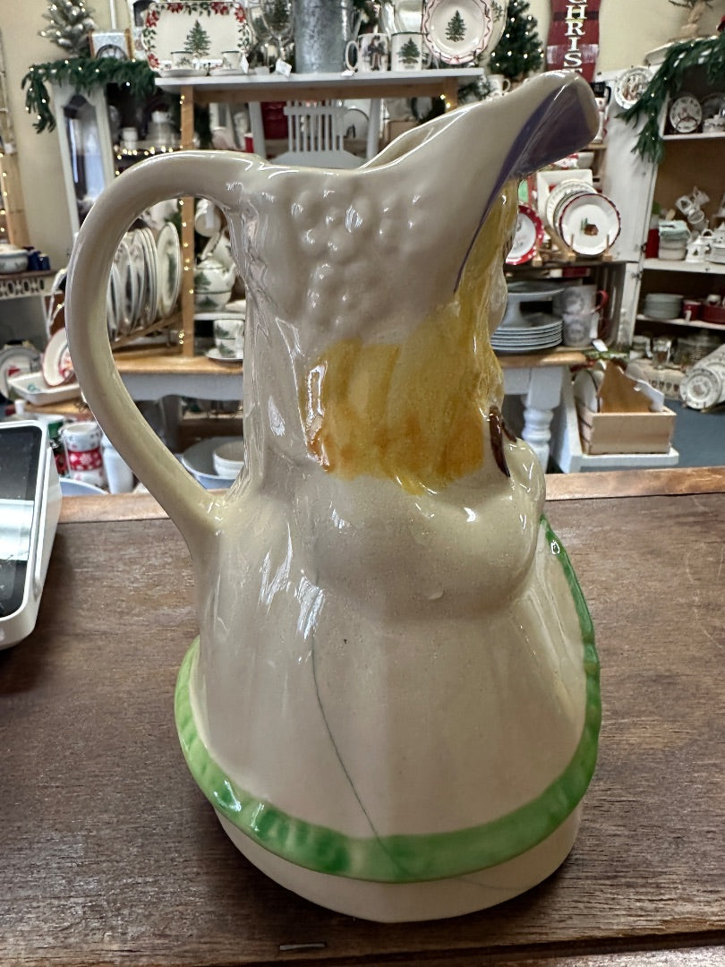 Ceramic pitcher angled view with painted bonnet, green base rim, curved handle