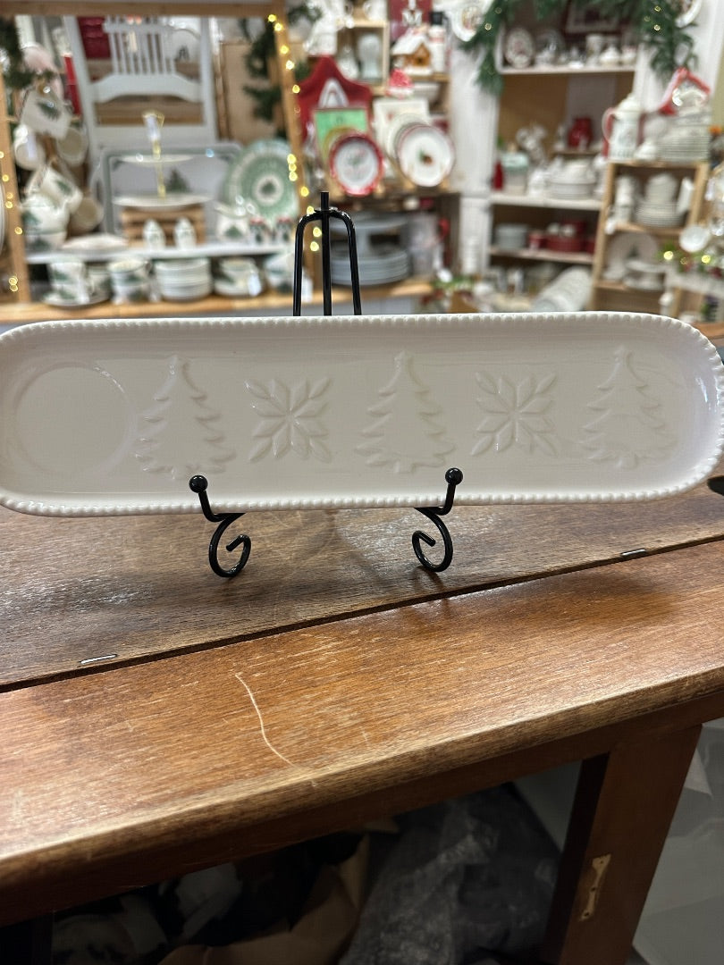 White oval holiday tray with embossed winter motifs and two black display hooks