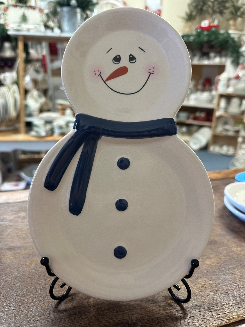 Snowman-shaped ceramic plate with blue scarf and smiling face on metal stand
