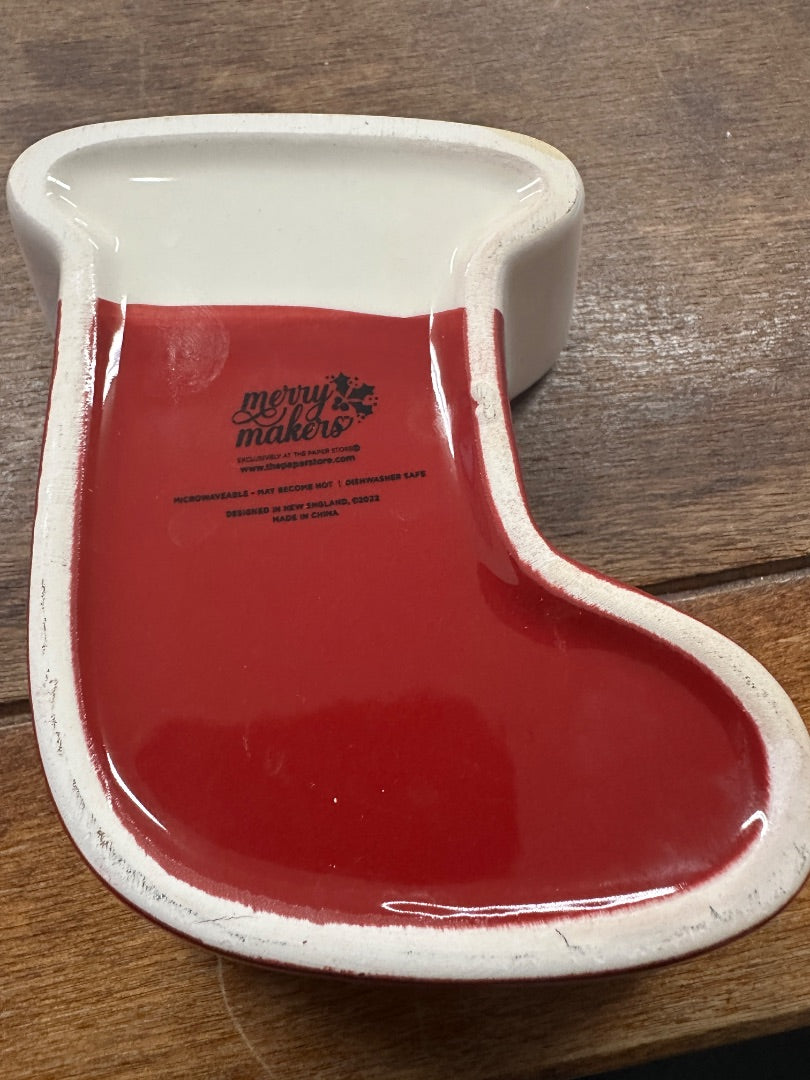 Red and white ceramic stocking-shaped bowl with Merry Makers logo on back