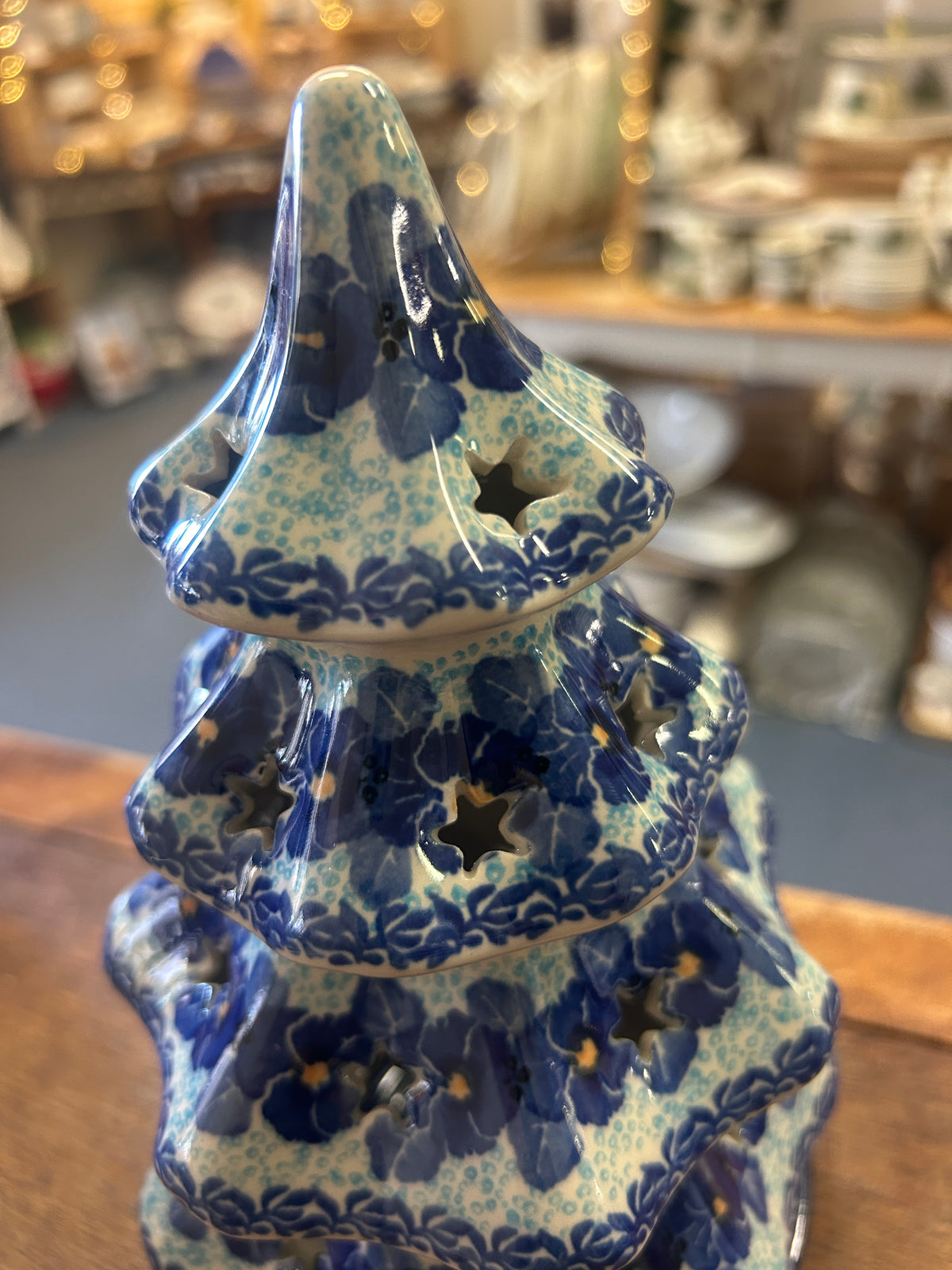 Blue ceramic tree luminary with floral motif and tiered silhouette, angled view