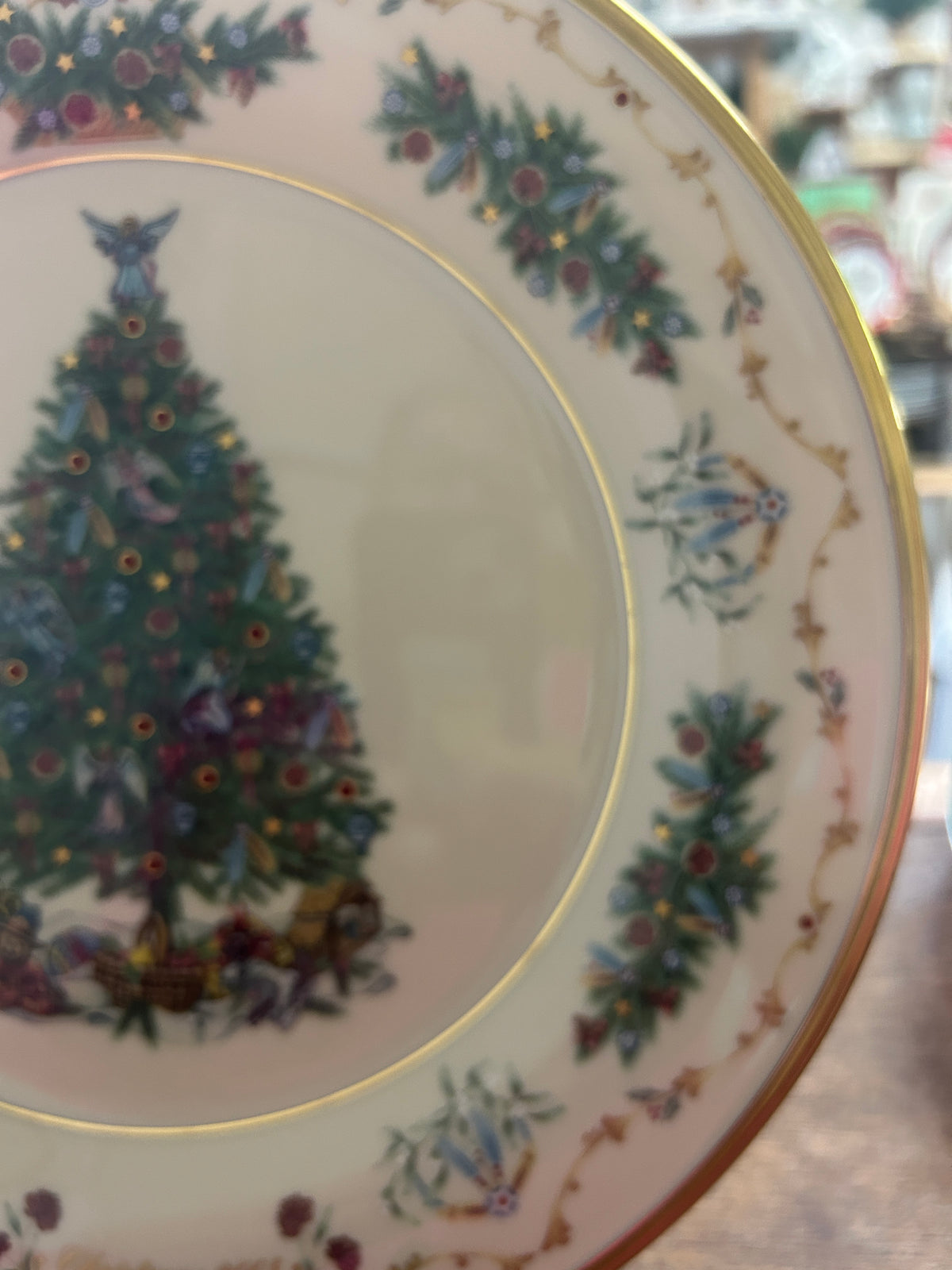 Christmas plate detail: painted tree, blue wreath motifs, and gold rim along the border