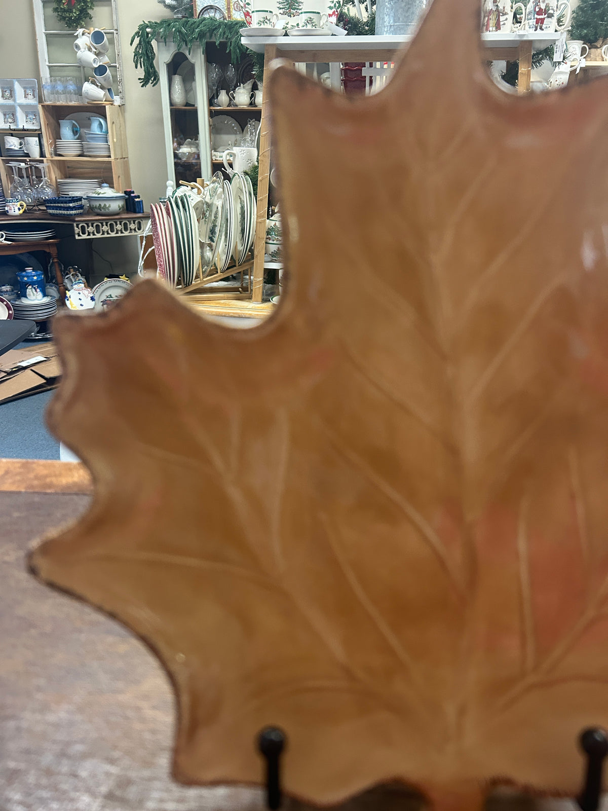 Brown leaf-shaped ceramic plate close view with black stand pegs