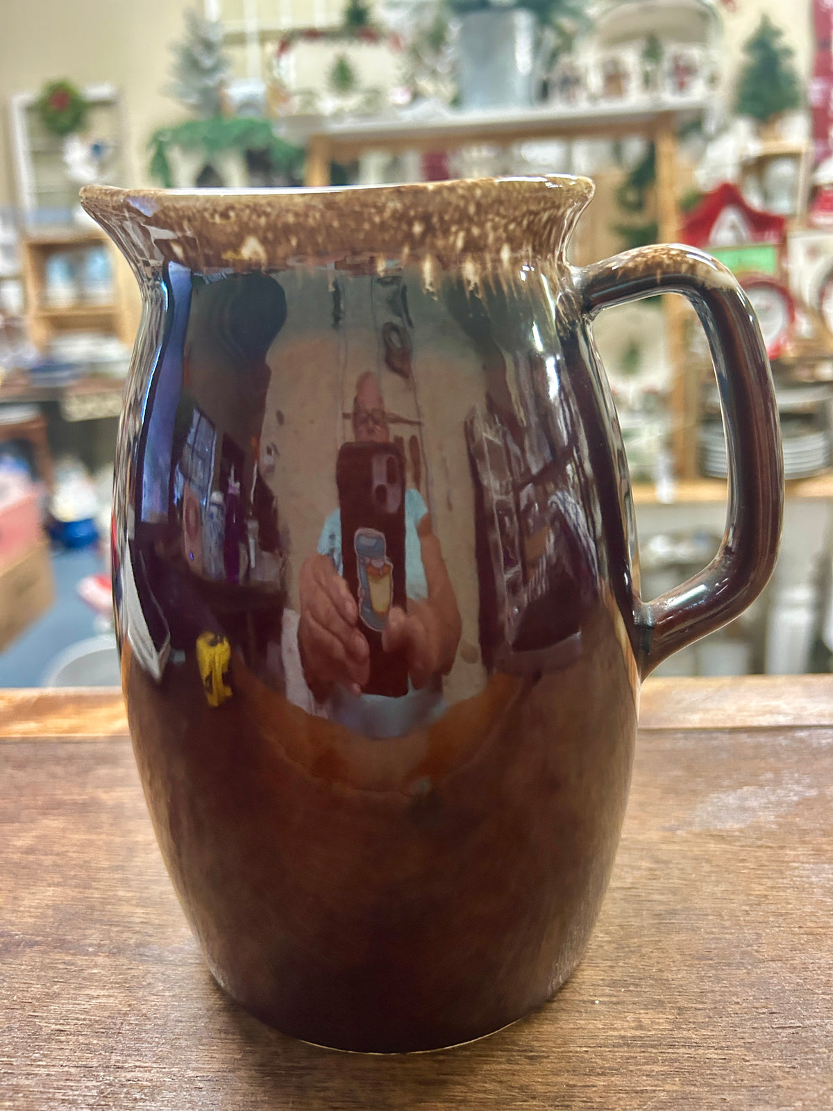Brown ceramic drip-glaze pitcher with curved handle and narrow spout.