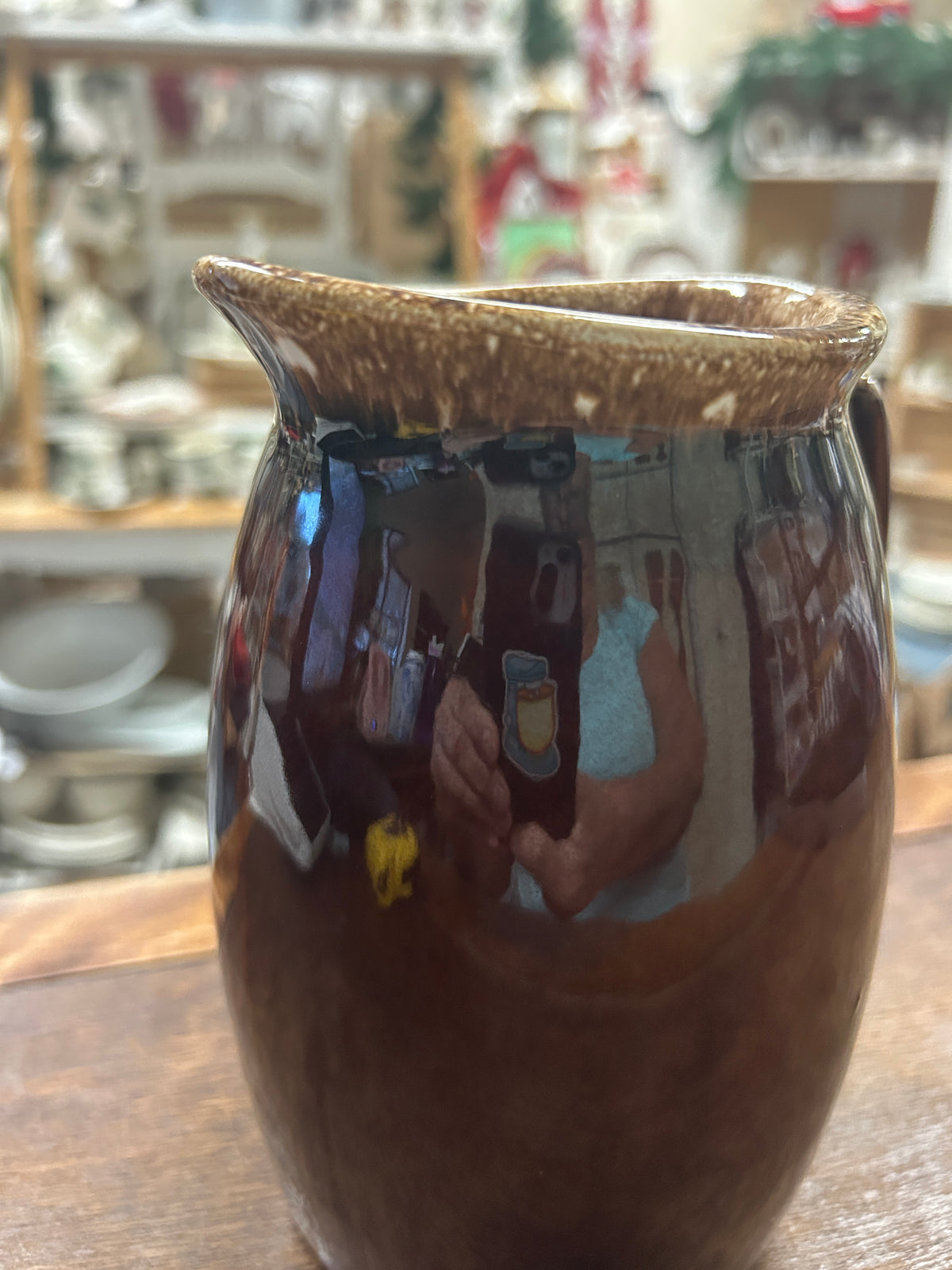 Brown ceramic pitcher with tall rim, drip-glaze finish, and curved handle.