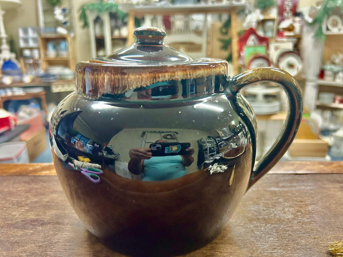 Brown drip ceramic bean pot with lid and loop handle, glossy glaze finish.
