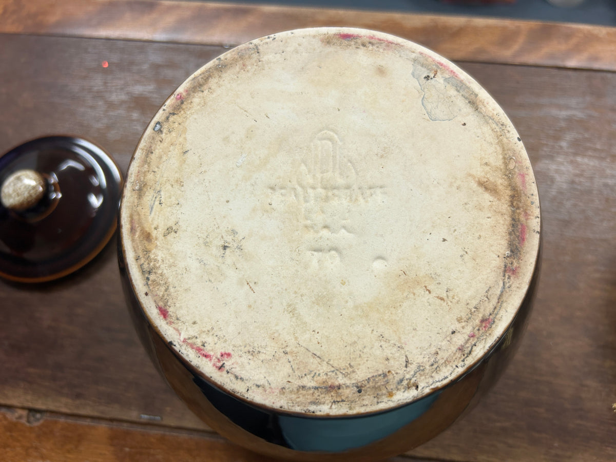 Bottom of brown glazed bean pot with lid knob posts and worn, speckled glaze.