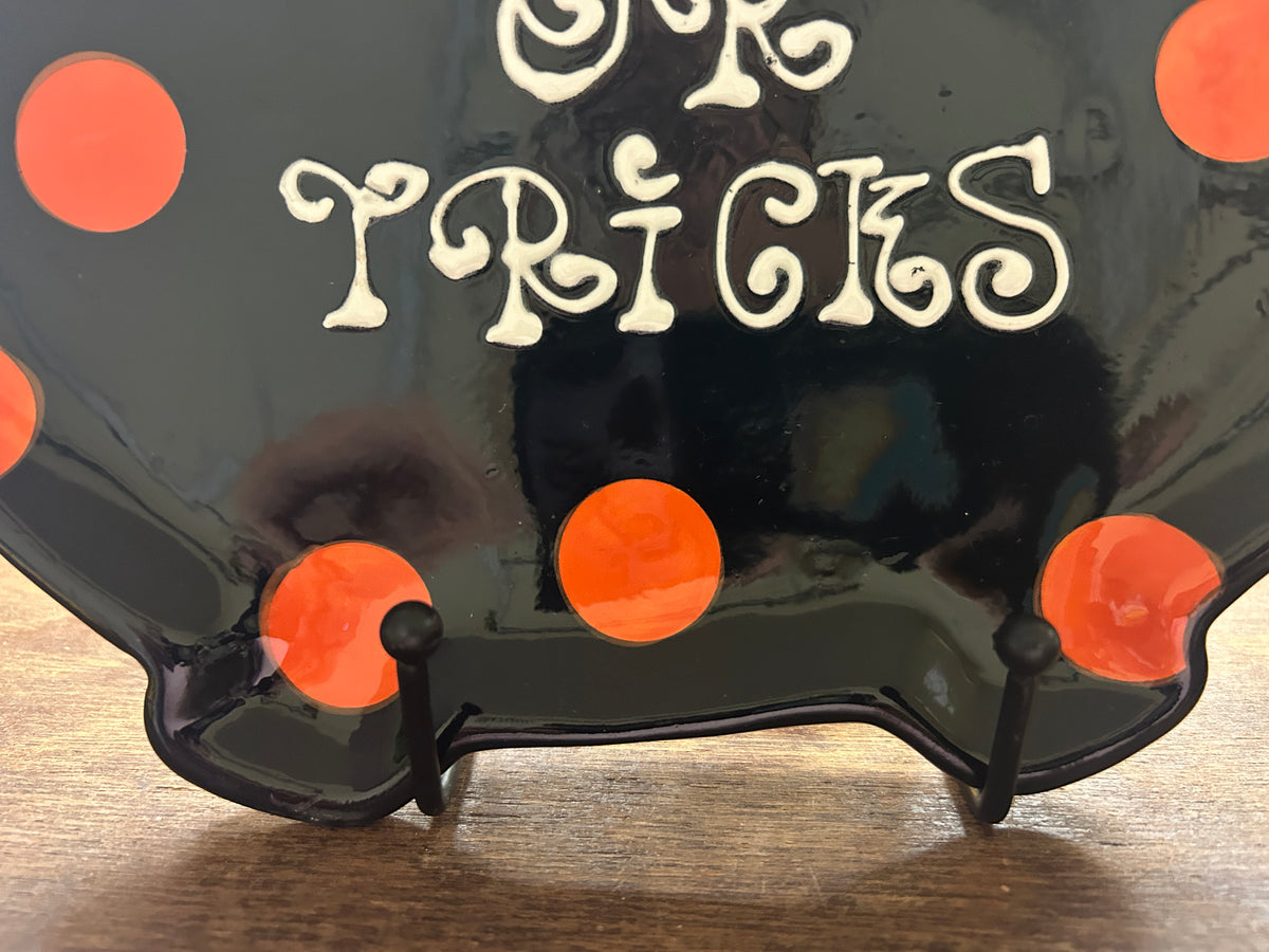Close-up of dark cauldron platter with orange dots and white 'Treats or Tricks' lettering
