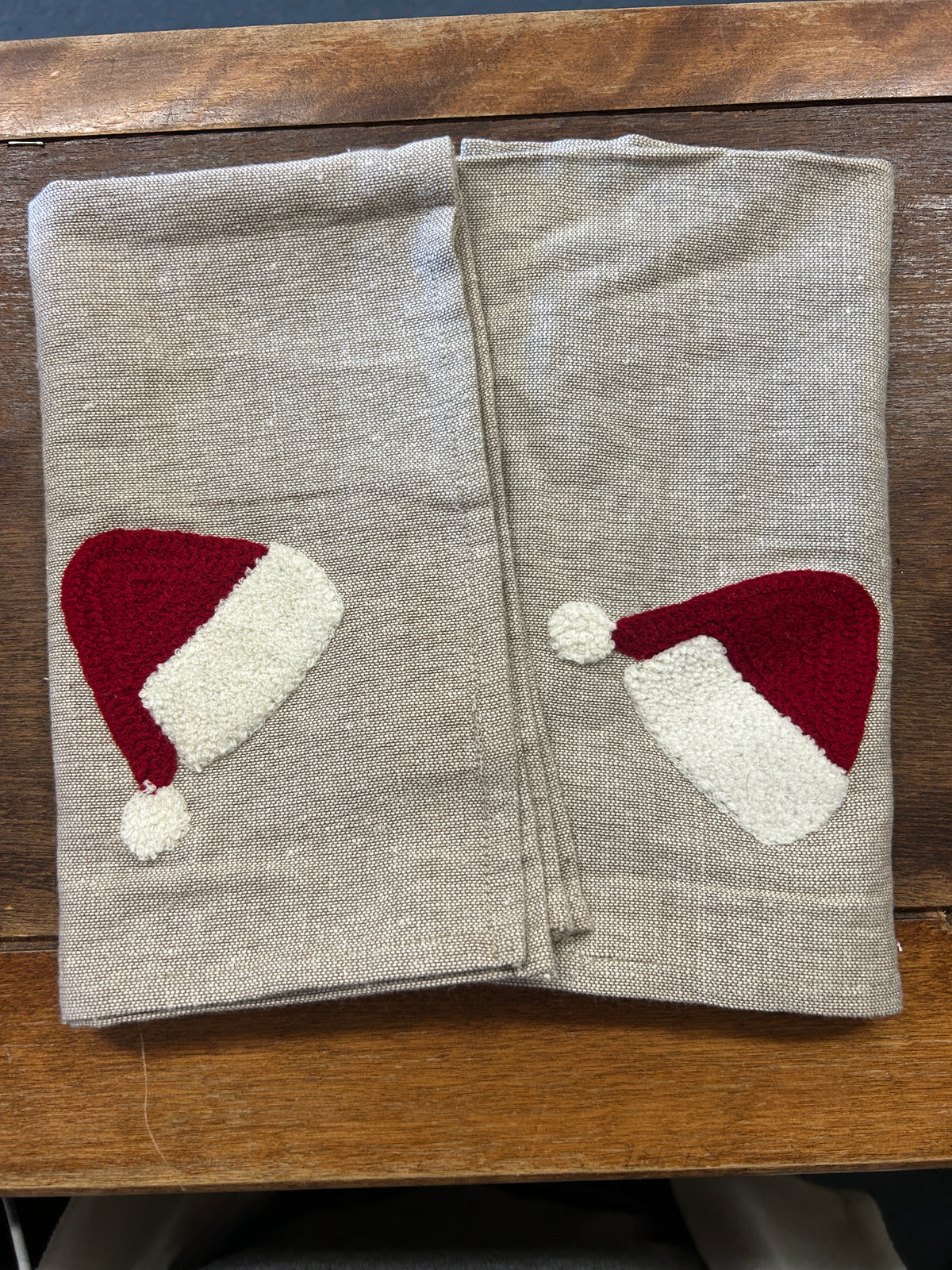 Set of 2 linen-style napkins with red and white Santa hat appliques, folded