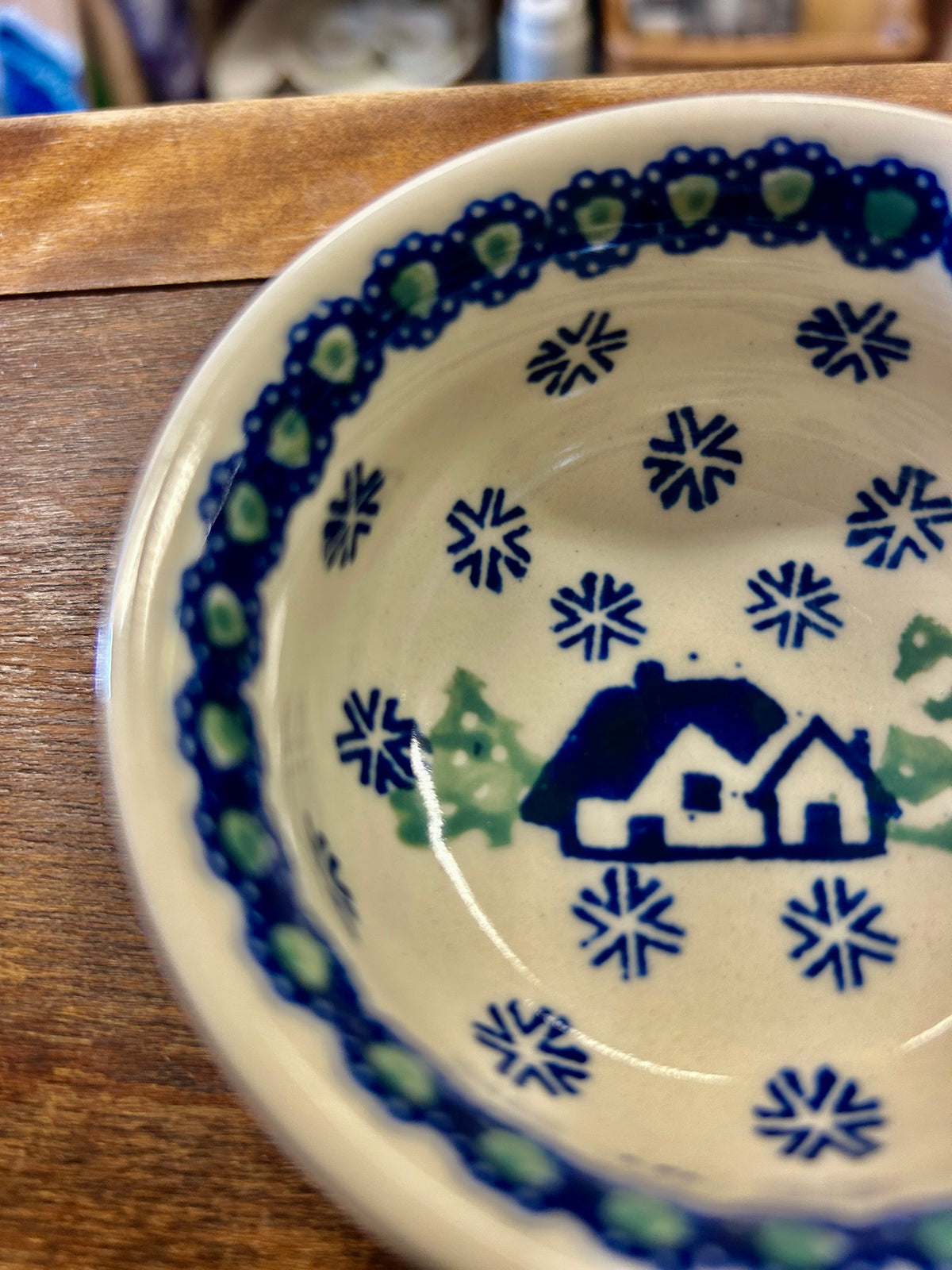 Polish pottery bowl interior with blue snowflakes and house motif, green accents