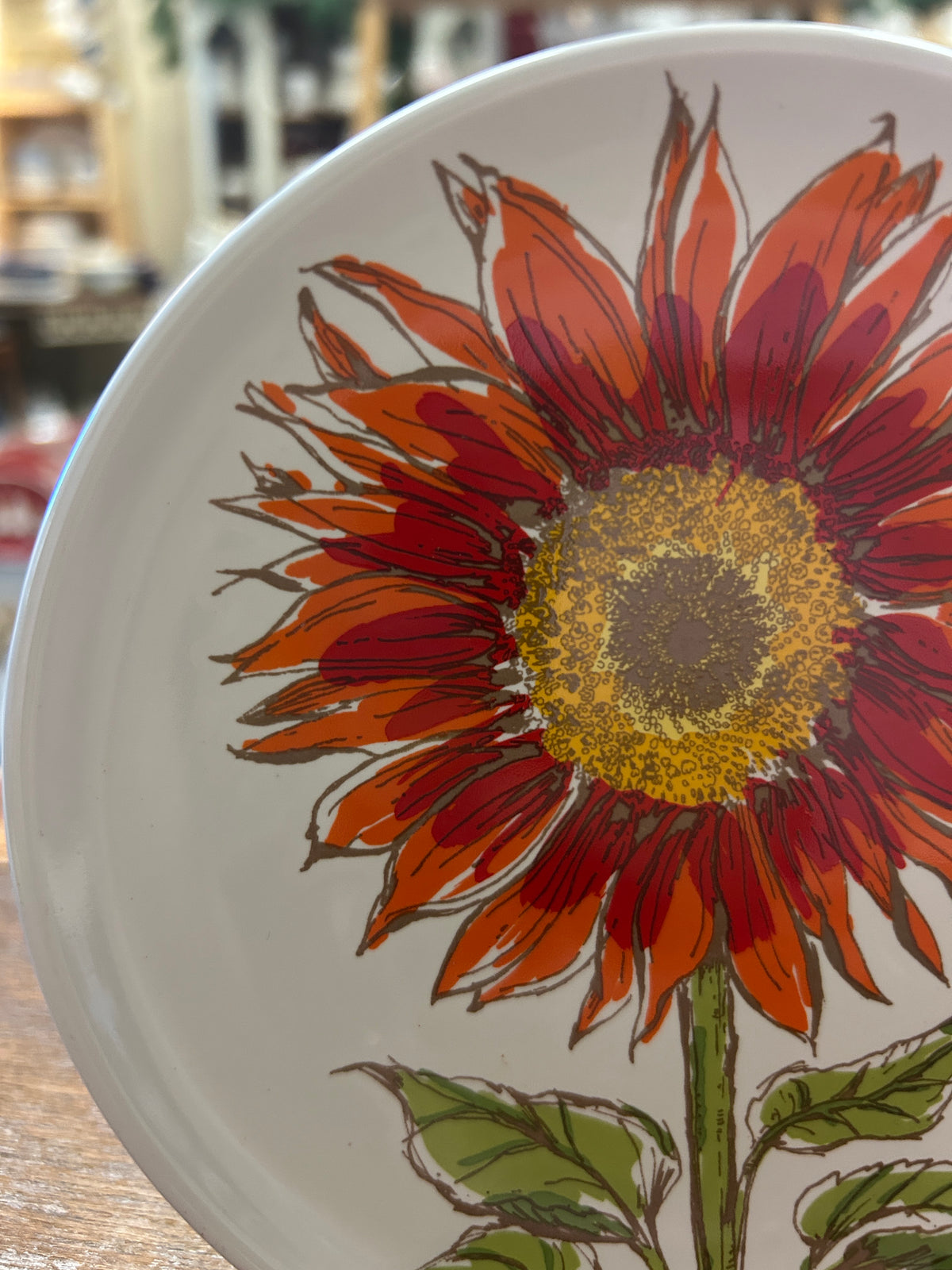 Close-up white plate with large red-orange sunflower illustration