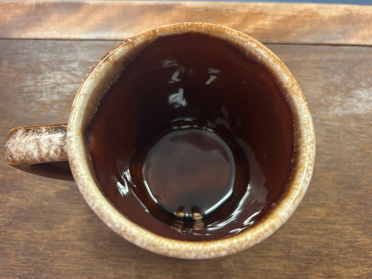 Top view of brown ceramic mug with speckled rim and dark glossy interior