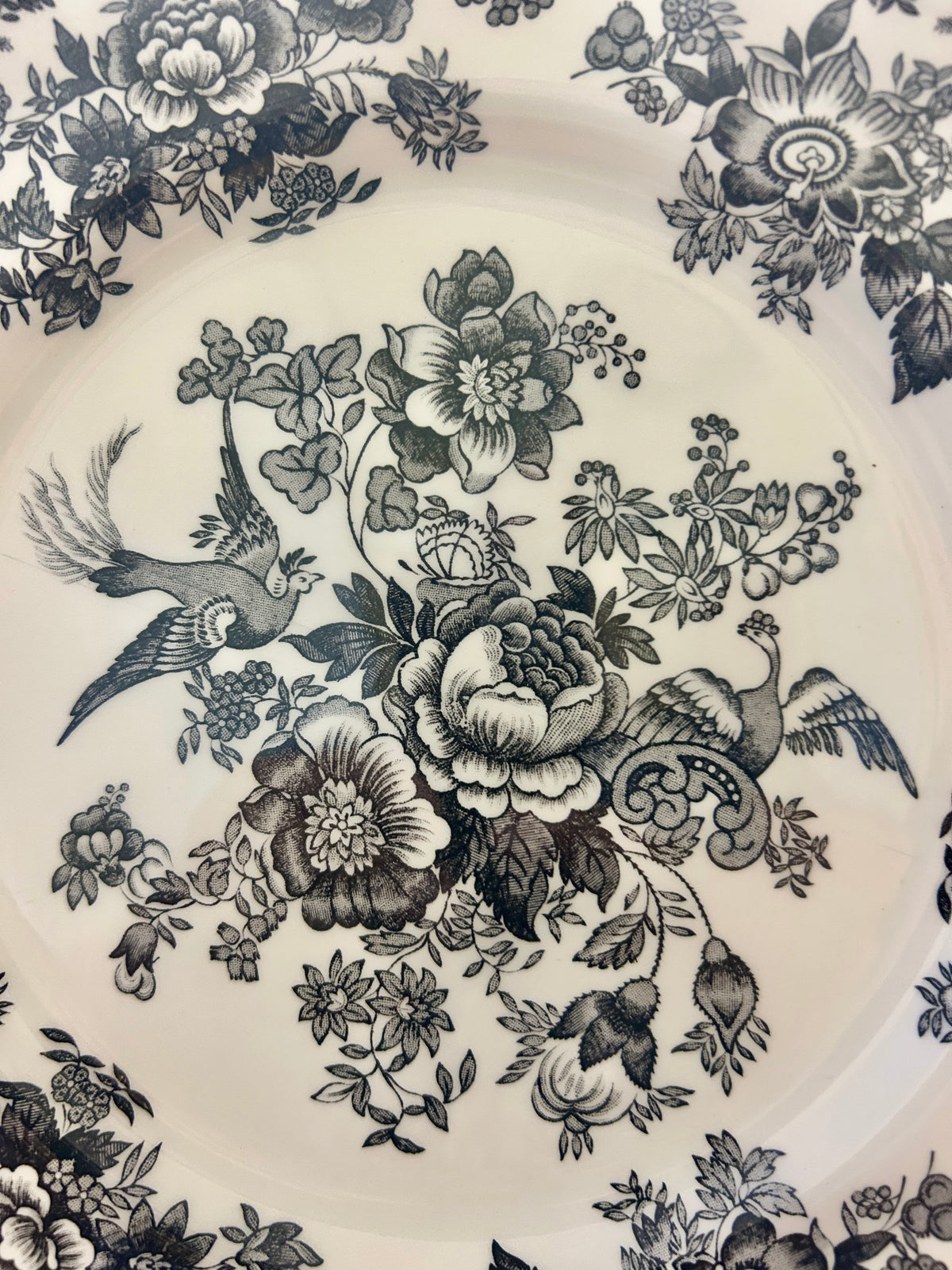 White porcelain plate top with blue floral bouquet and small birds, intricate border