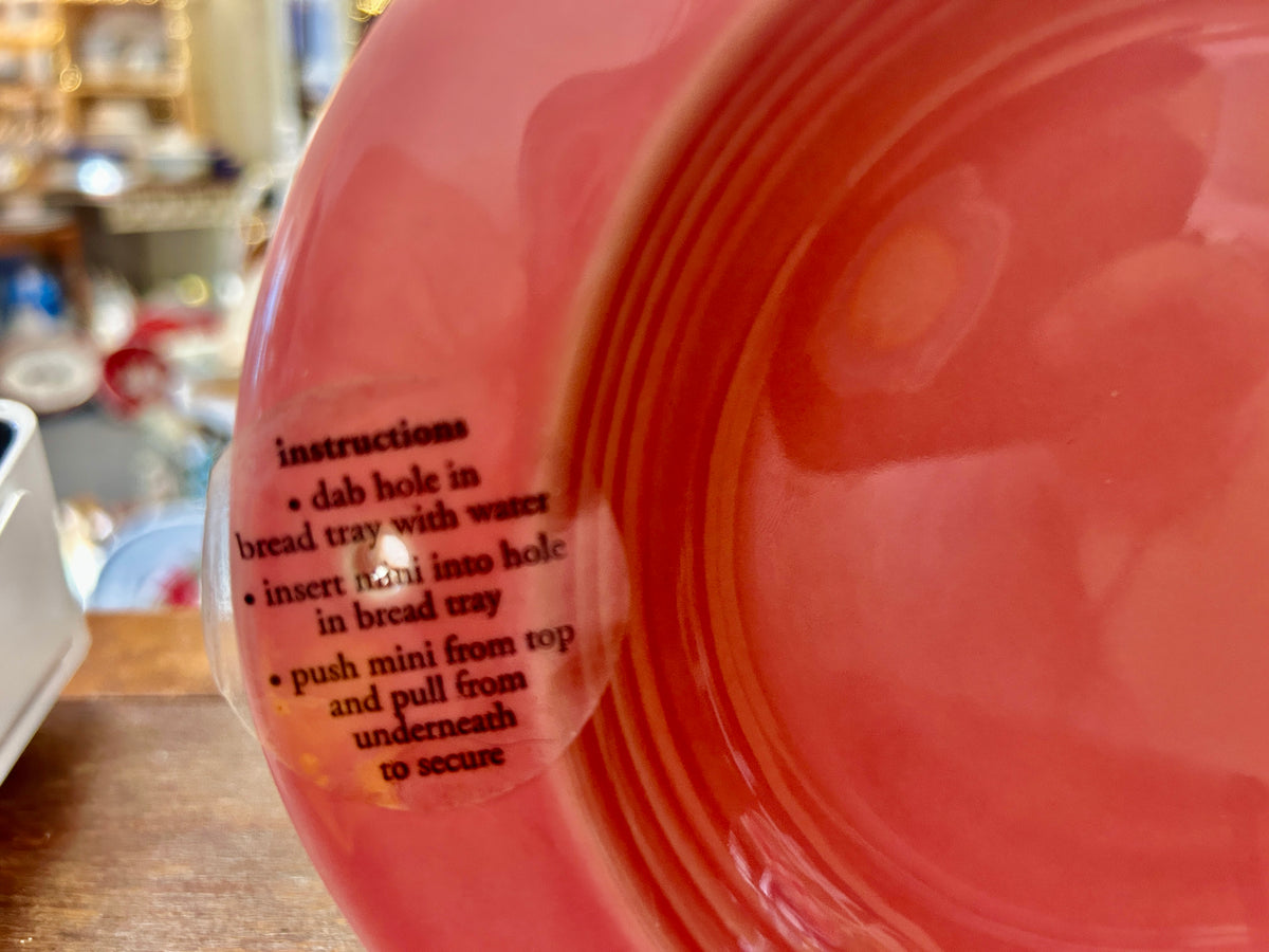 Pink ceramic platter side with raised text and ridged concentric design