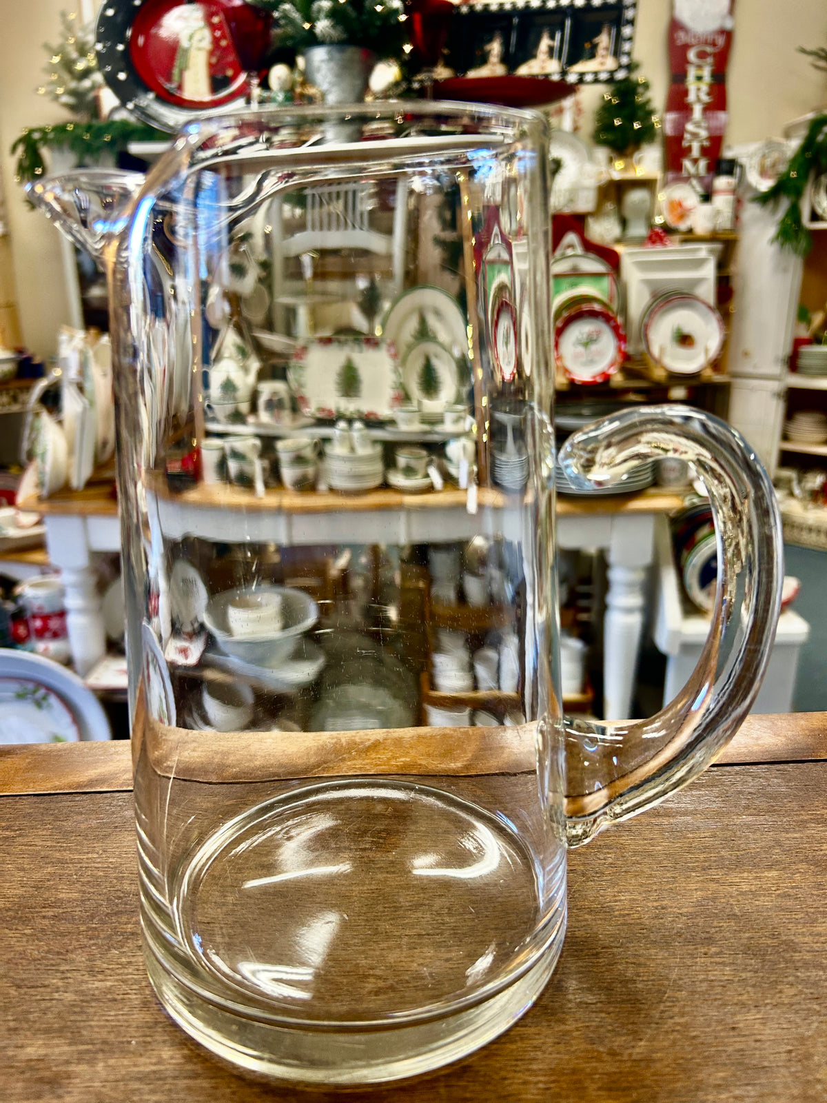 Clear glass pitcher with curved handle and rounded base, full spout visible