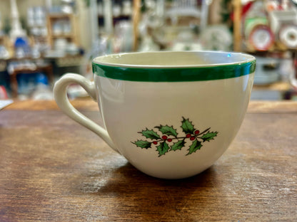 Ceramic Christmas cup with green rim and painted holly berries motif on front