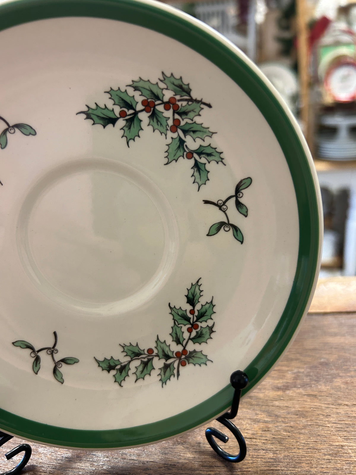 White Spode saucer plate with green rim and holly-and-berry wreath design