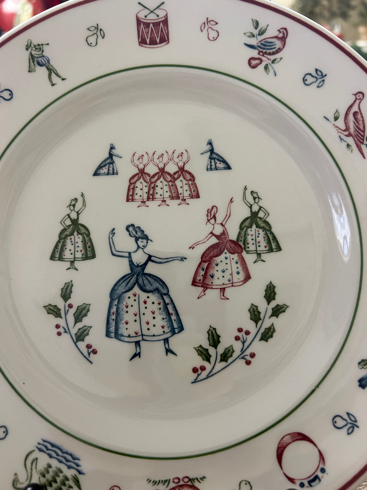 Multicolor Christmas plate with central group of dolls and wreath border, white ceramic.