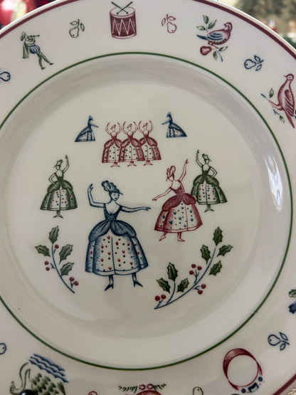 Multicolor Christmas plate with central group of dolls and wreath border, white ceramic.
