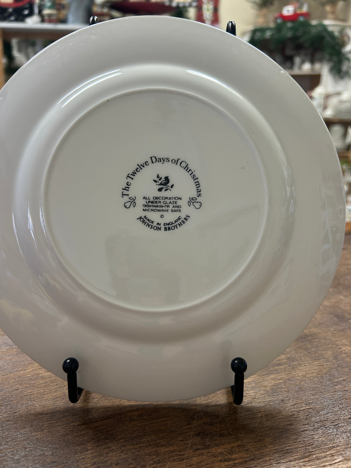 White decorative plate back with stamped maker text and date, on black stands