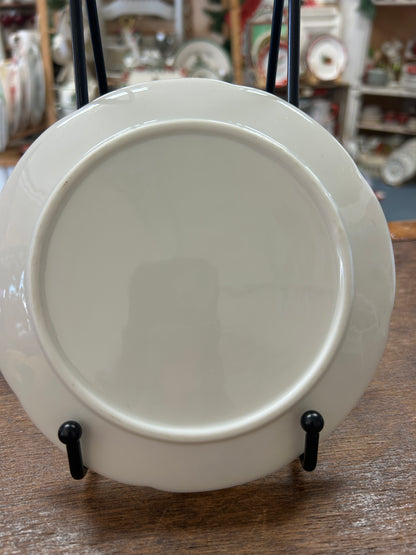 Plain white round plate with small stand feet, smooth back surface.