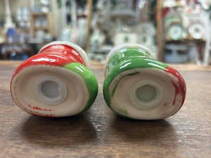 Undersides of red and green dog-shaped salt and pepper shakers with openings
