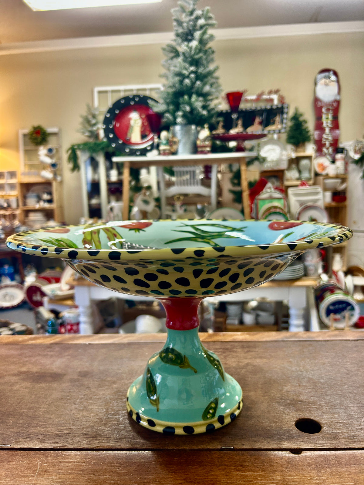 Multicolor vegetable pedestal bowl with leafy-and-veggie pattern on a green stand