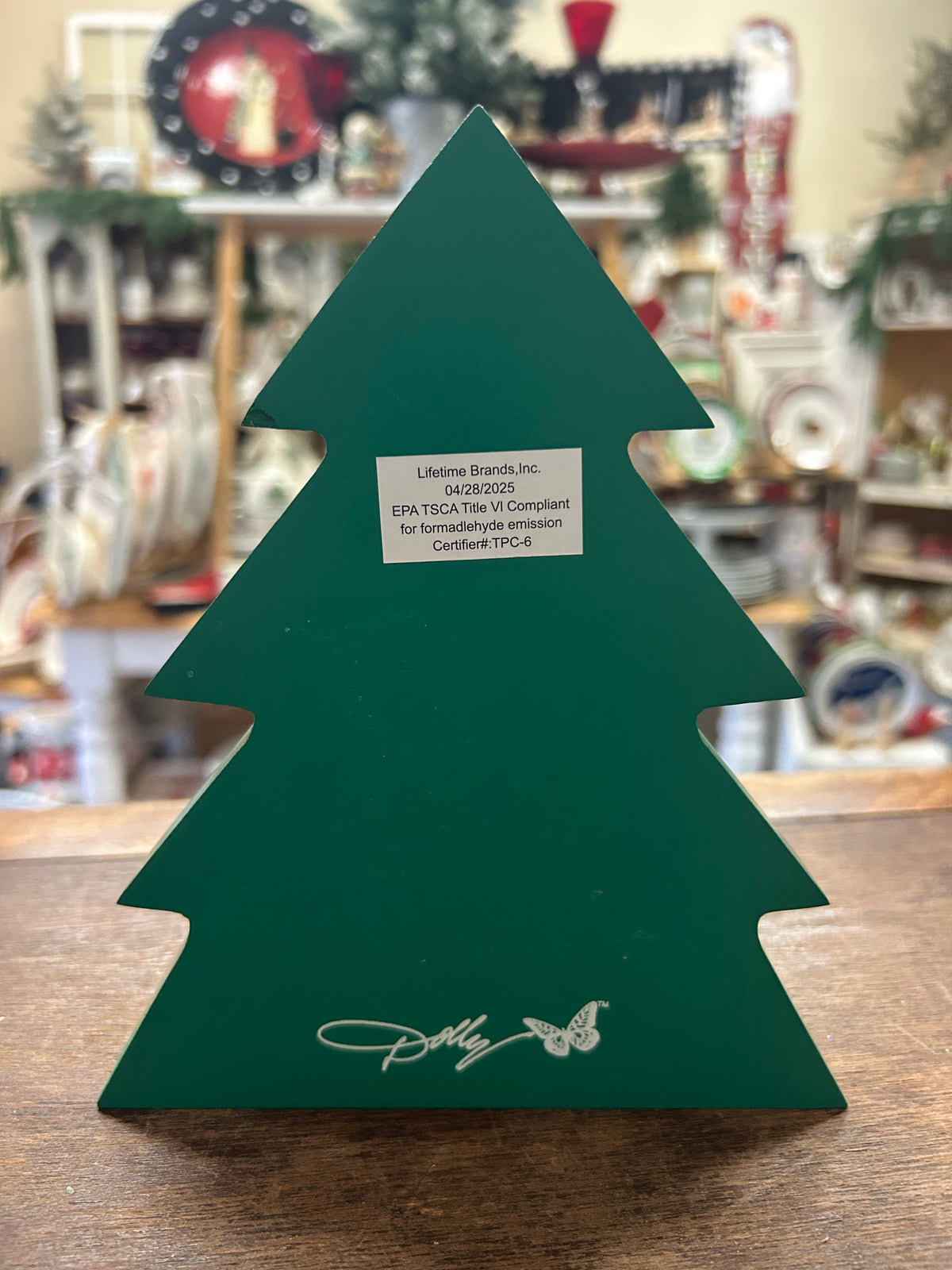 Green wooden Christmas tree back with branding, butterfly, and certification label