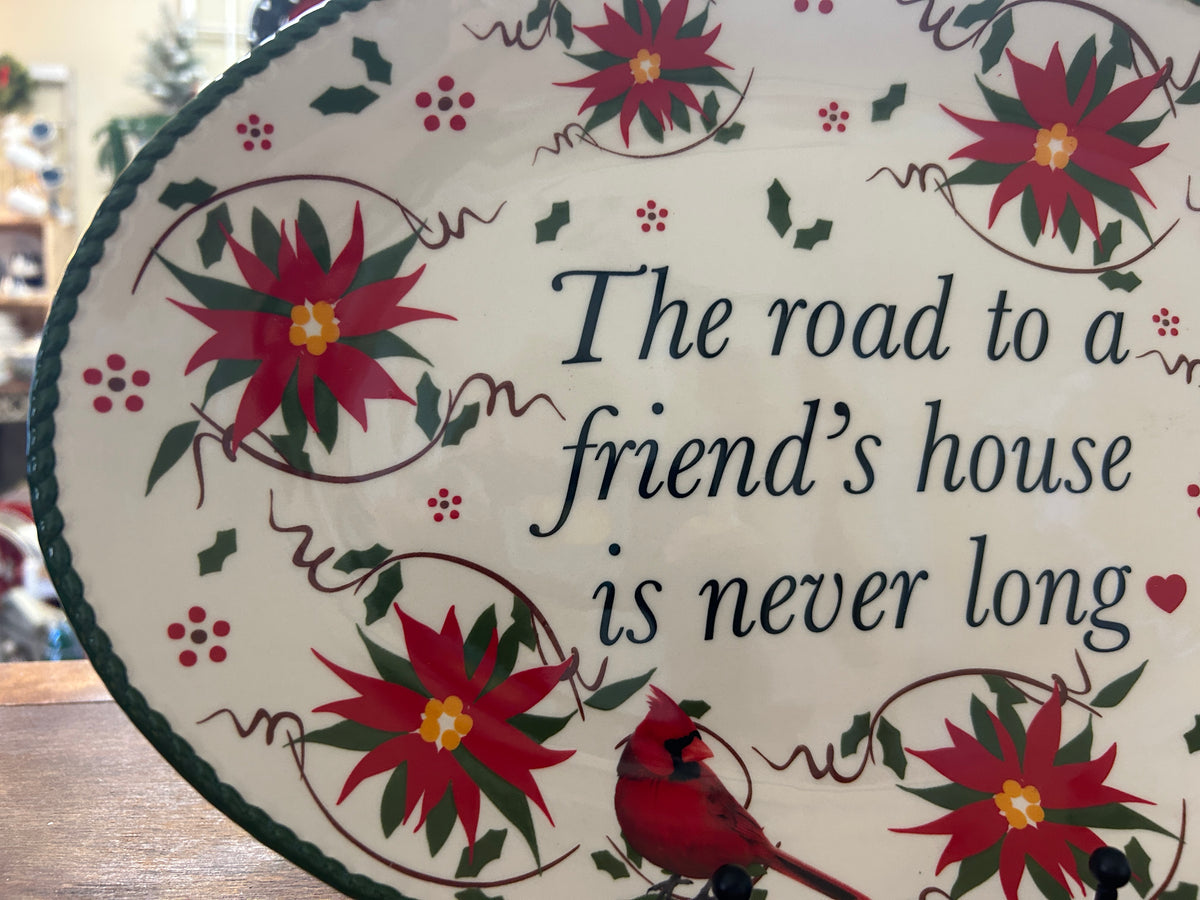 Close-up oval platter with green border, red flowers, and cursive holiday quote