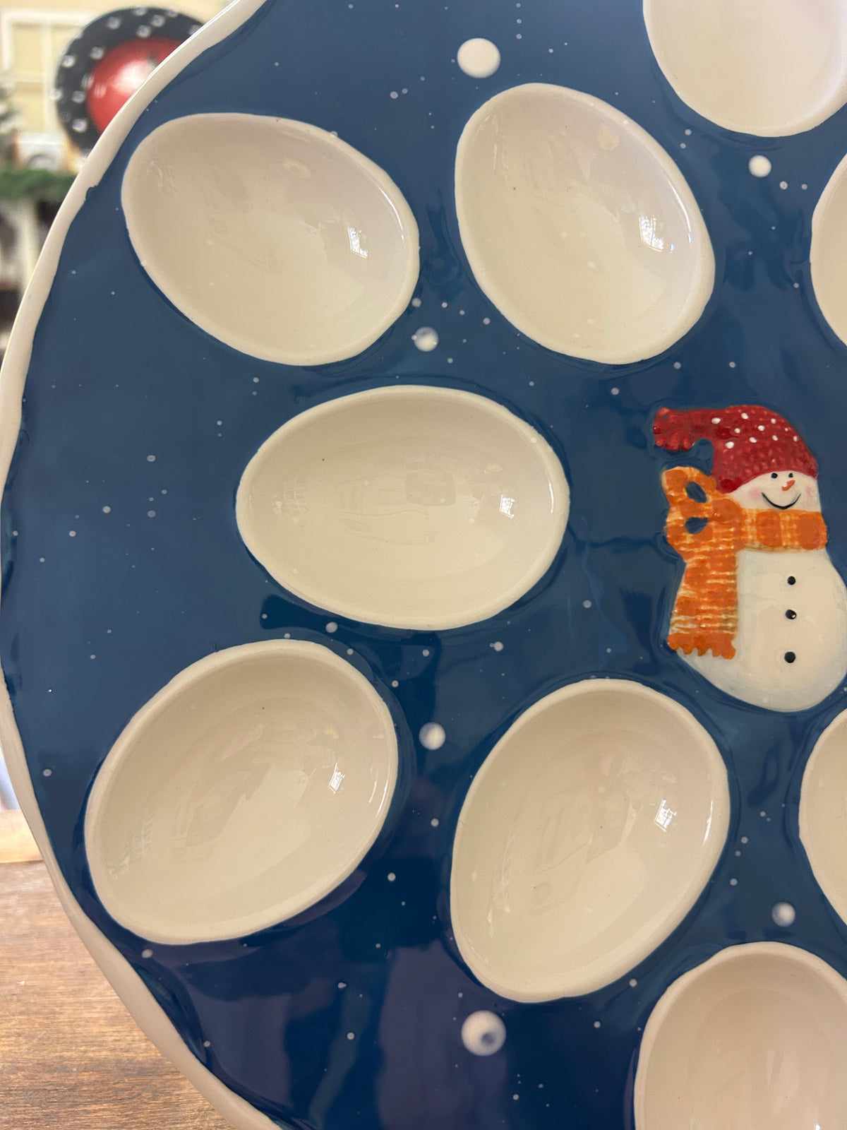 Blue ceramic deviled egg tray close-up with white egg cups and snowman decoration