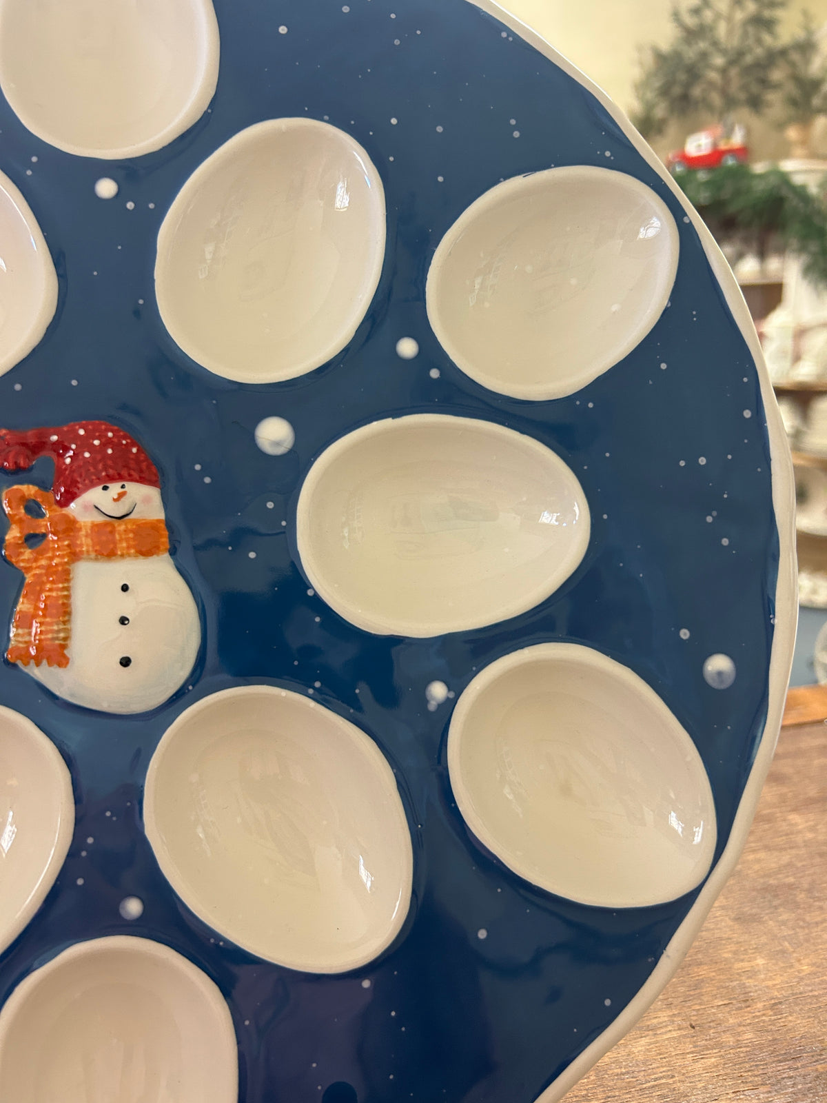Blue ceramic deviled egg tray with snowman side detail and white oval egg cups
